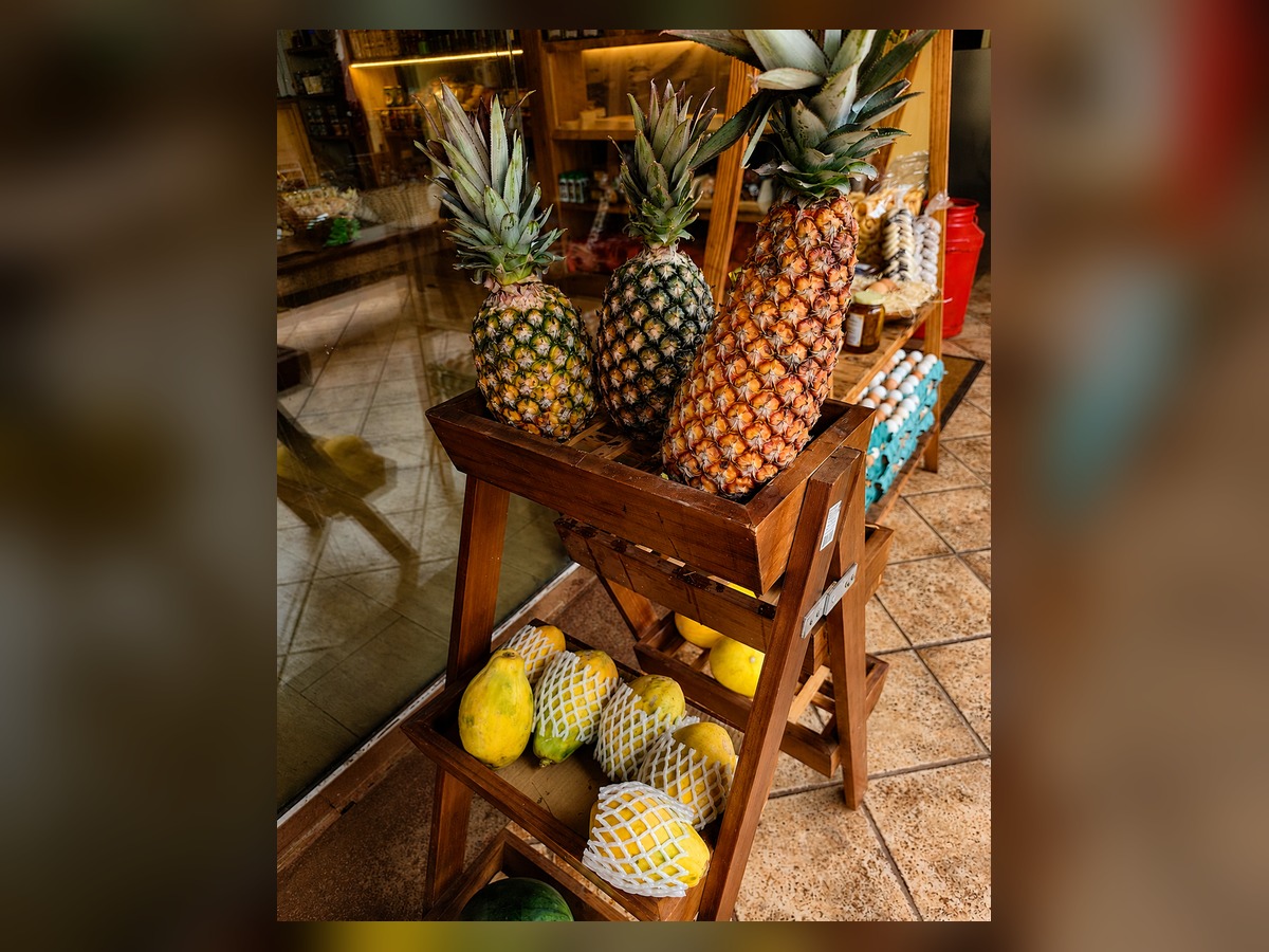Abacaxis e mamões frescos em escada de madeira na entrada do empório