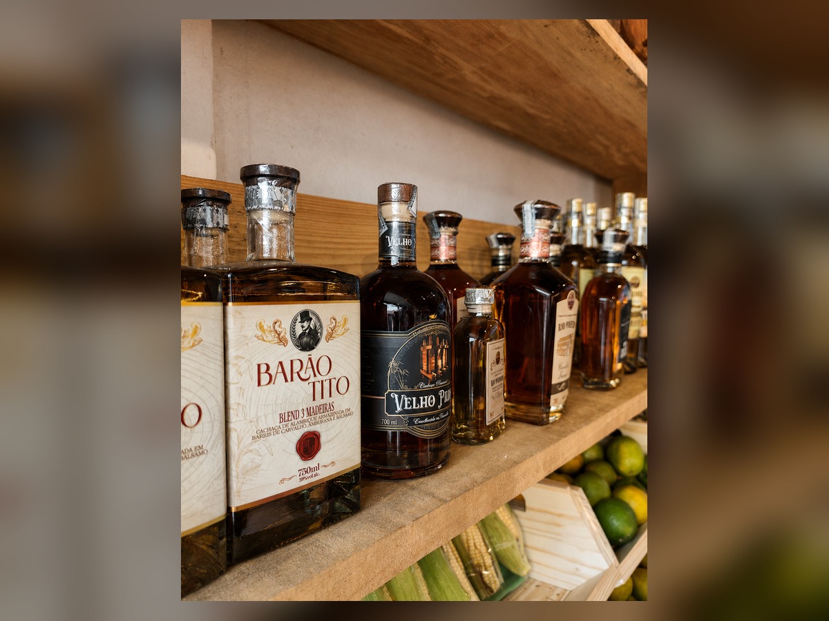 Garrafas de cachaça artesanal mineira na prateleira de madeira do empório