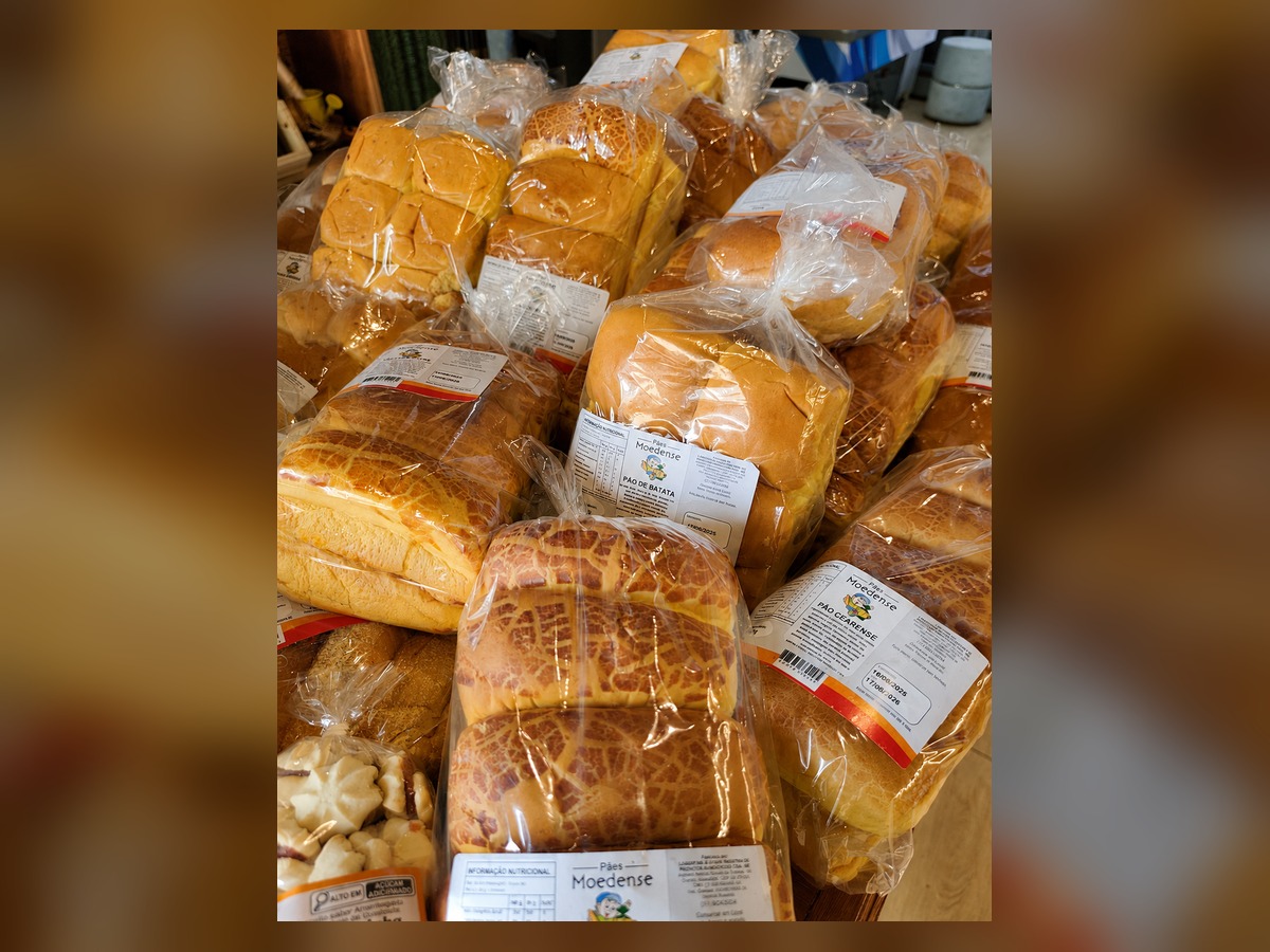 Pães e quitandas artesanais embalados sobre a mesa central do empório
